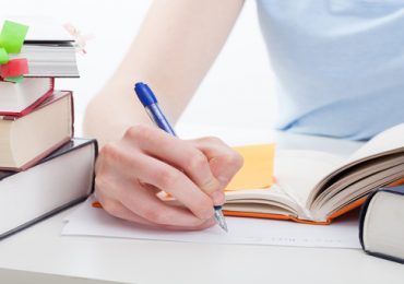 Student reading a book and writing the notes